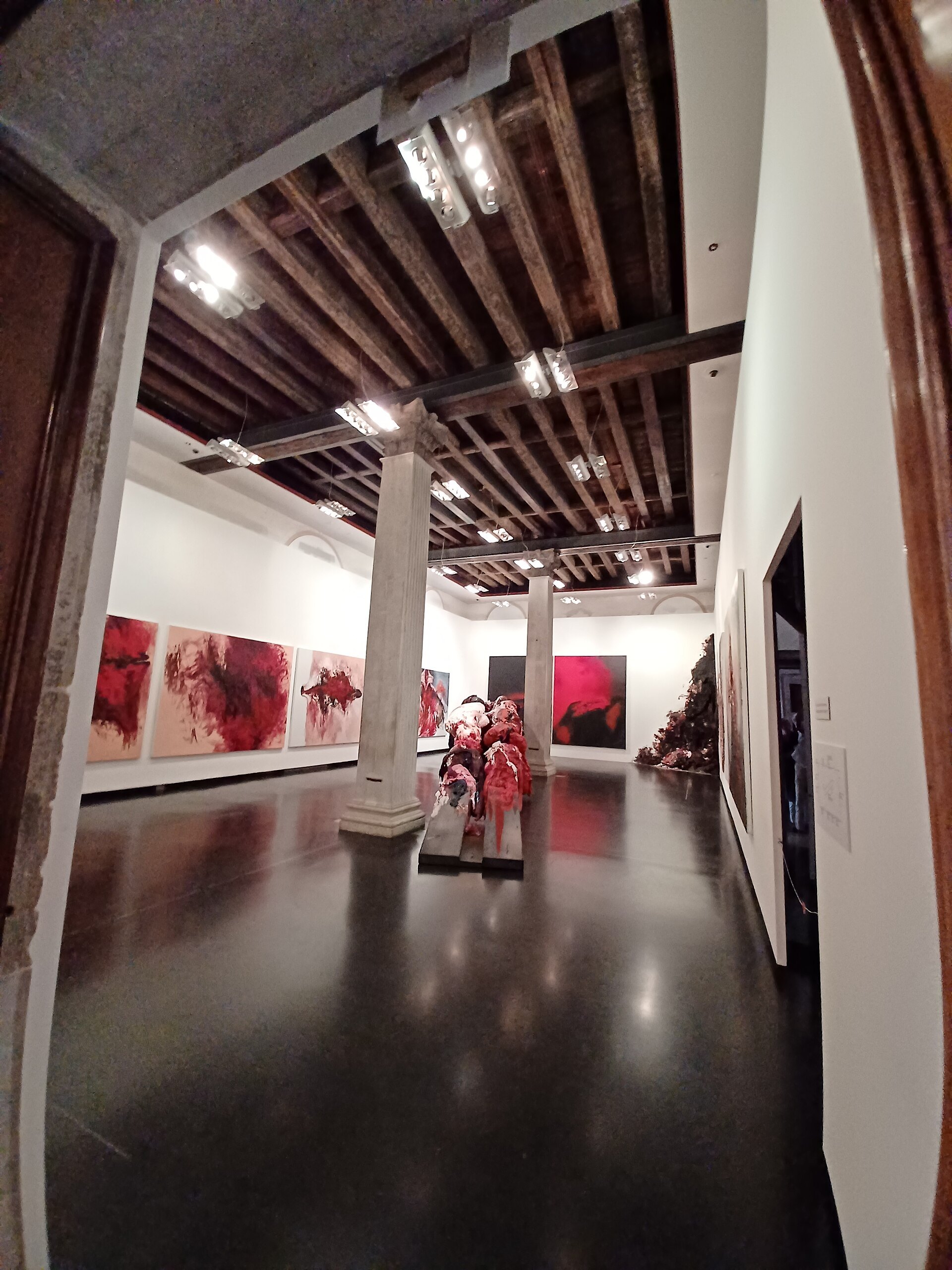 A gallery inside the Accademia, paintings hung along a long wall under a beamed ceiling
