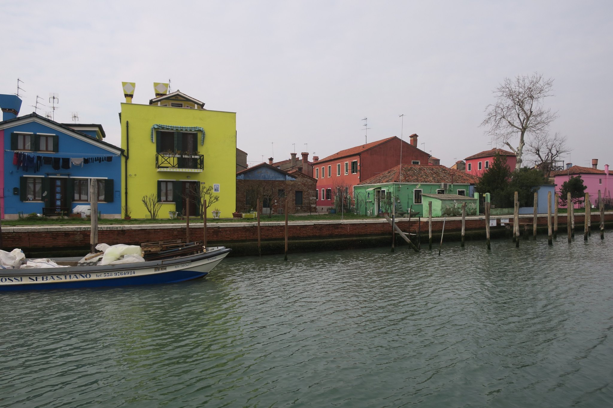 The waterfront at Burano with boats drawn up and coloured houses behind