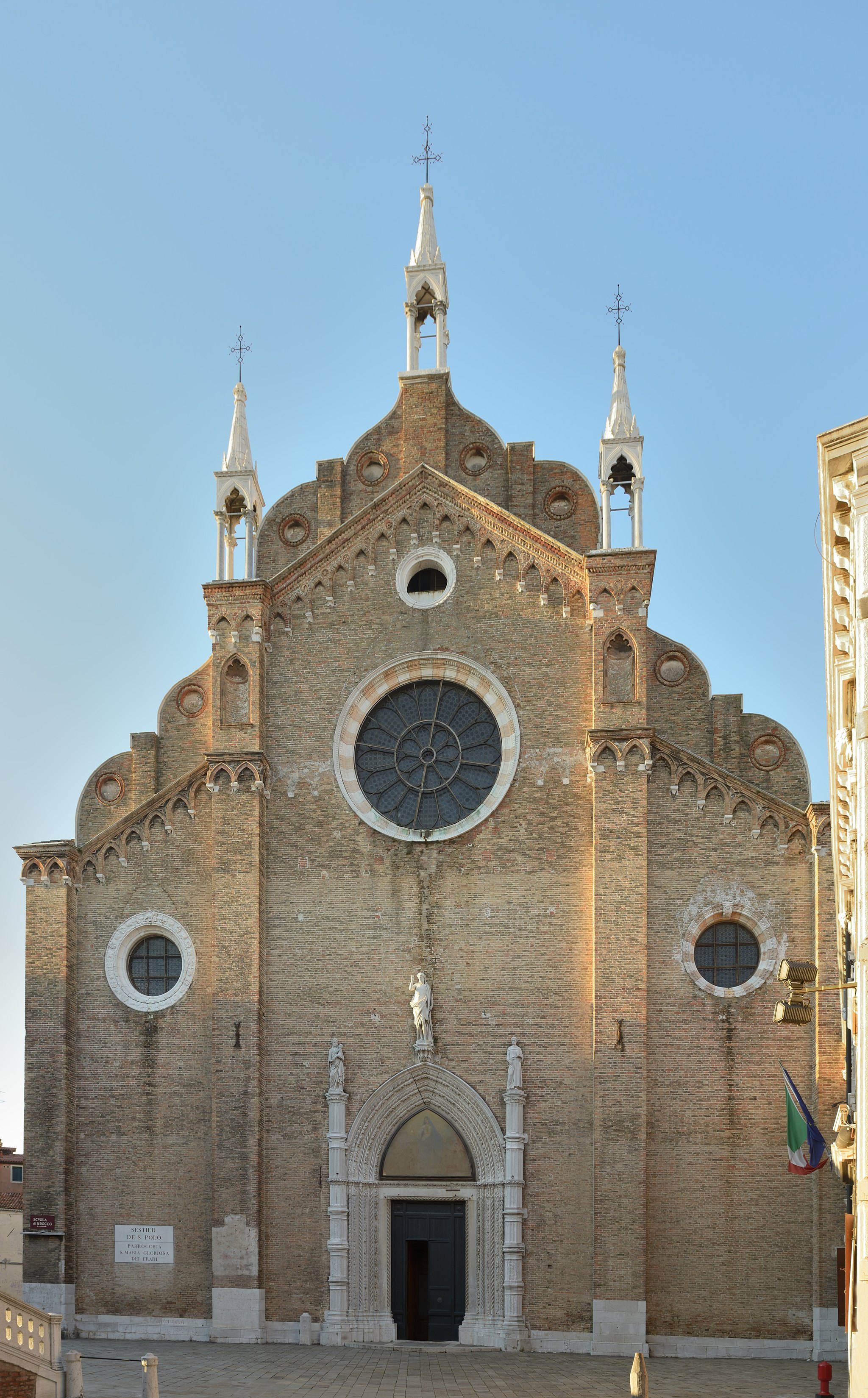 The brick front of the Frari, a wide Gothic façade with a rose window and almost no ornament