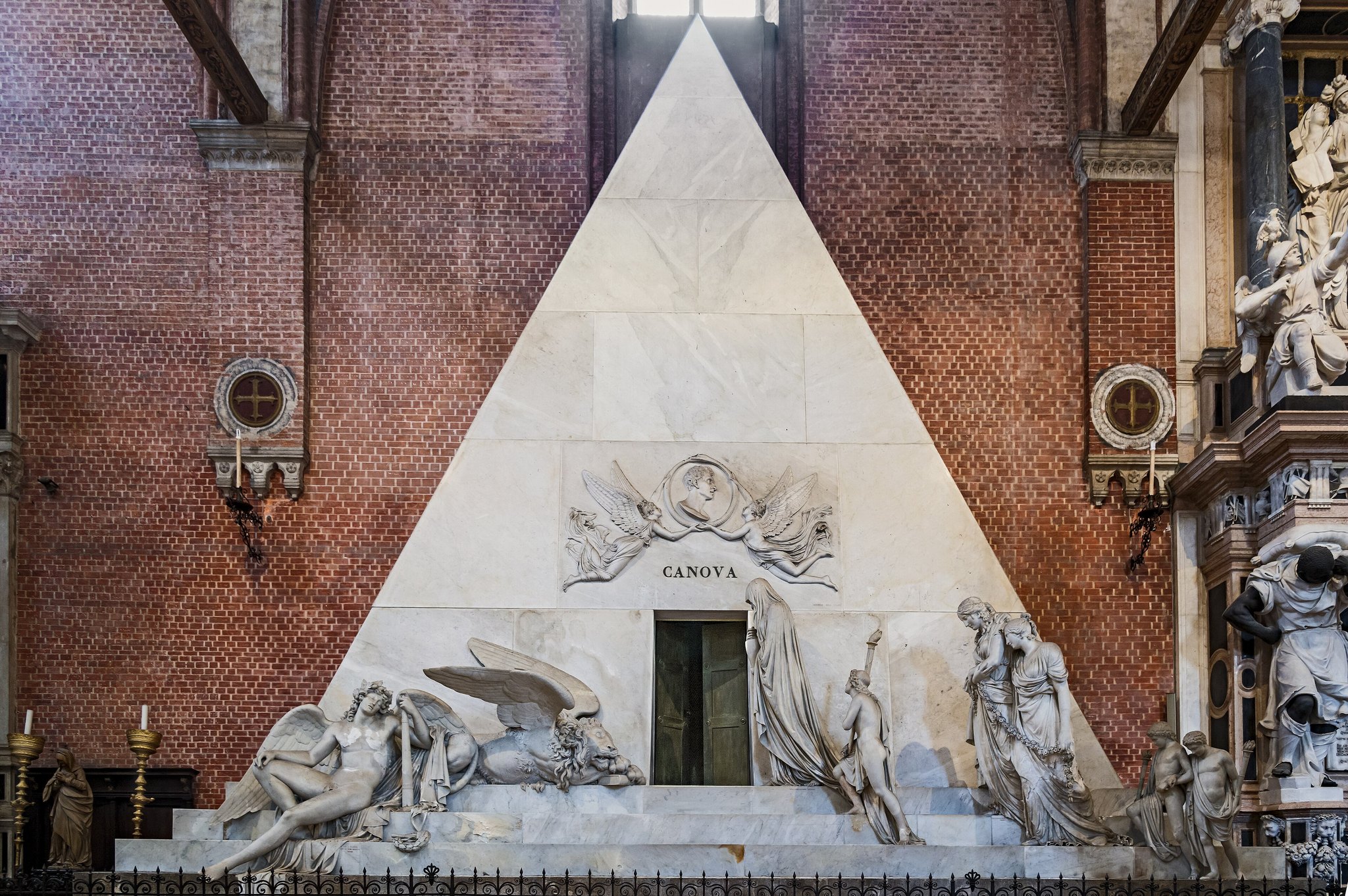 Canova's pyramid tomb inside the Frari, a marble doorway with mourning figures on its steps