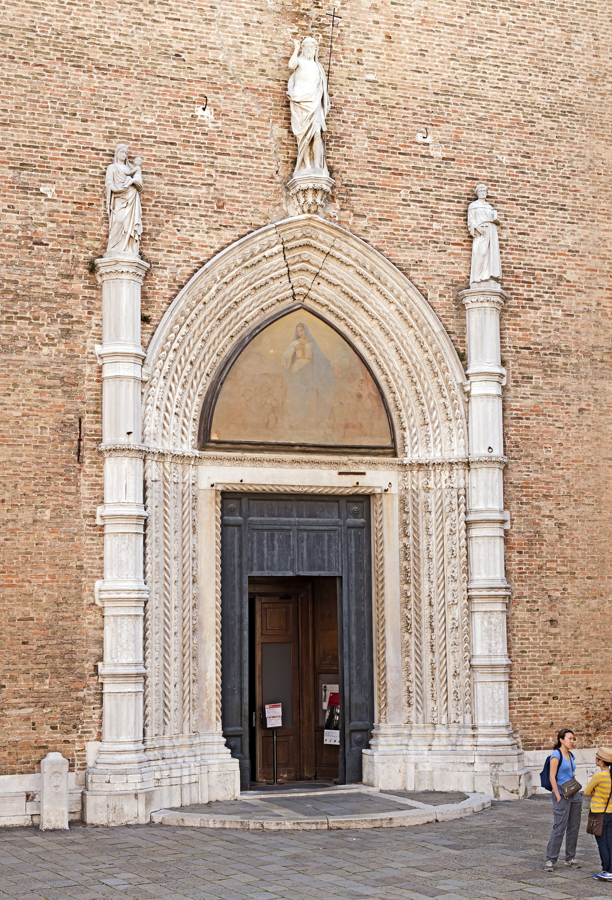 The main door of the Frari, a pointed brick arch with a marble figure above it