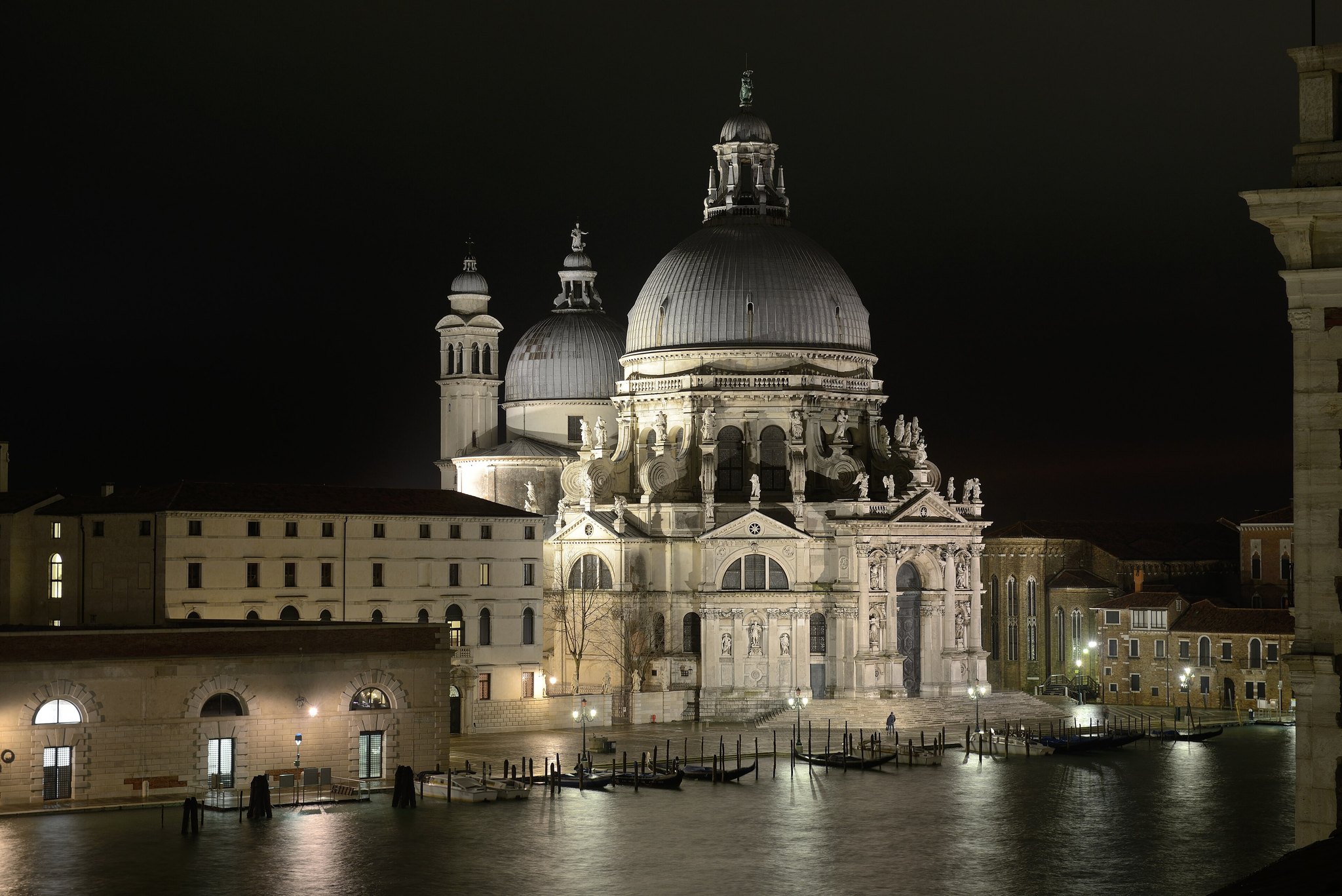 Santa Maria della Salute lit at night, the dome and lantern pale against a black sky