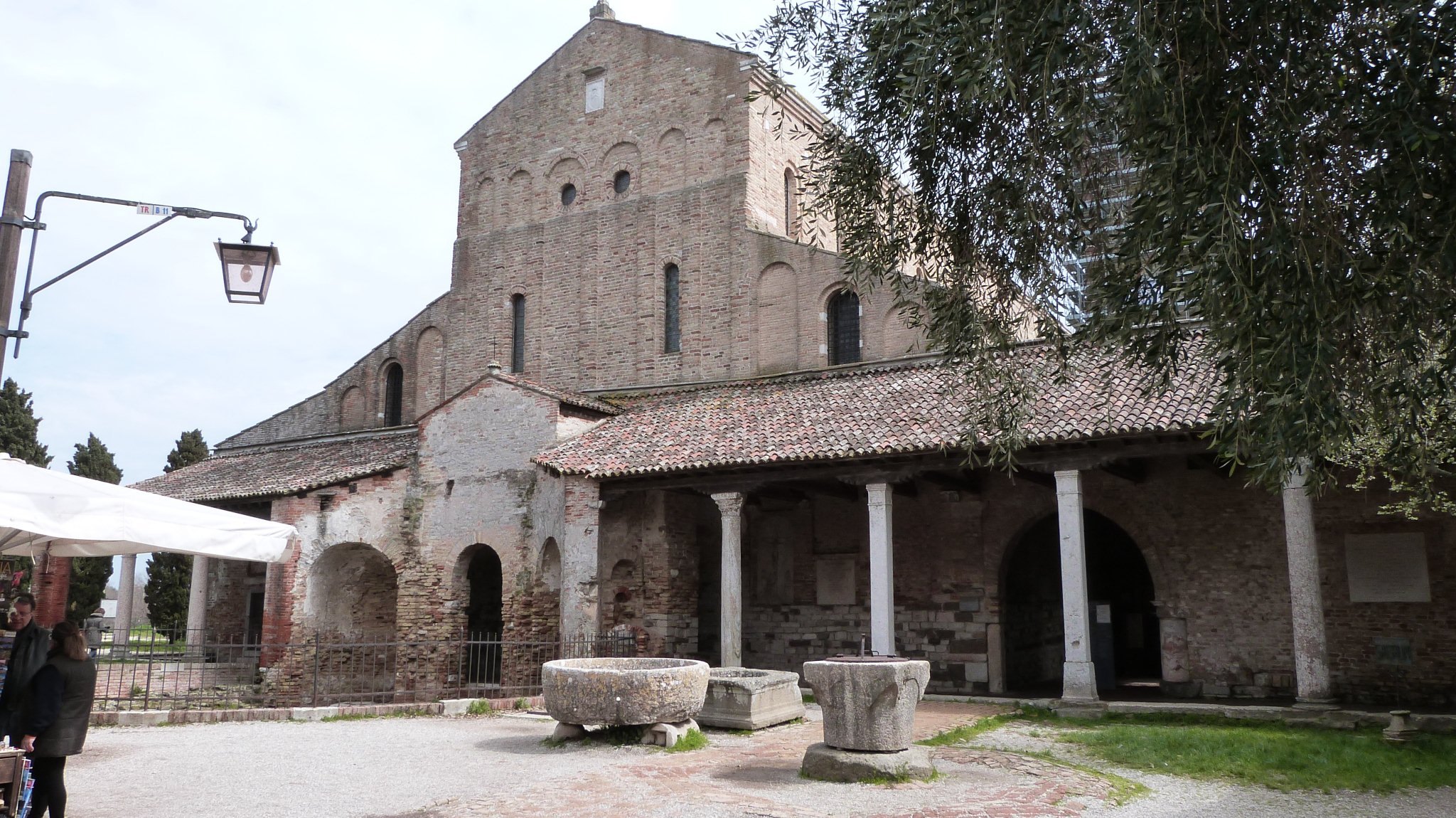 The portico of Torcello's cathedral, stone benches and columns along the front